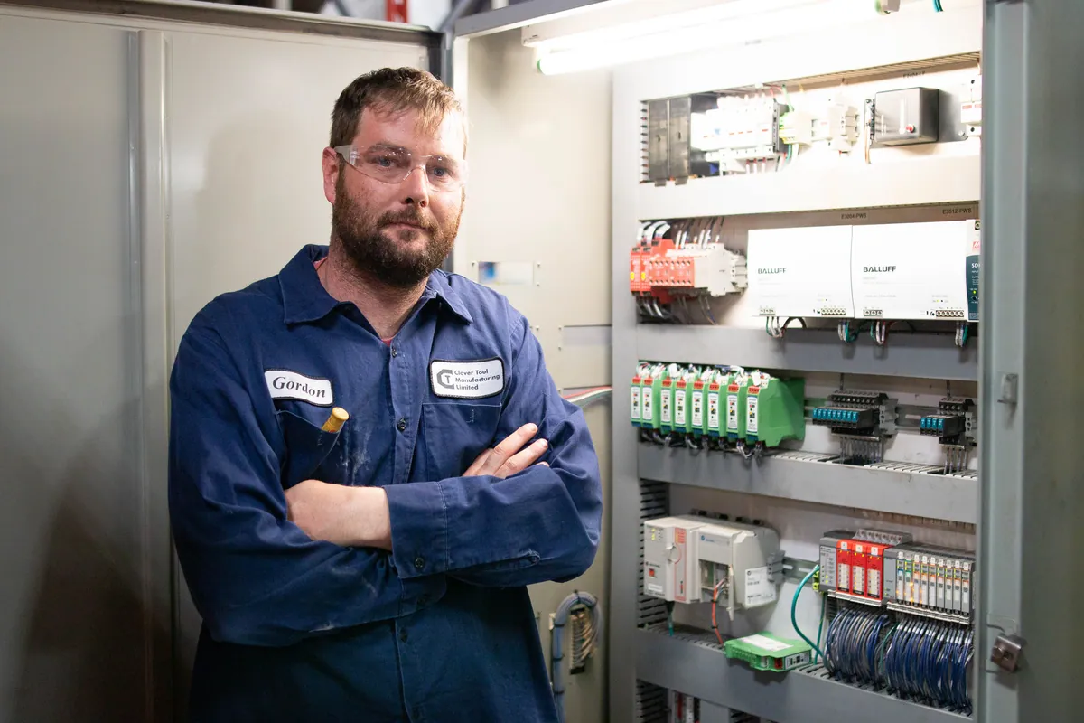 A Clover maintenance technician at an electrical control cabinet on the shop floor.