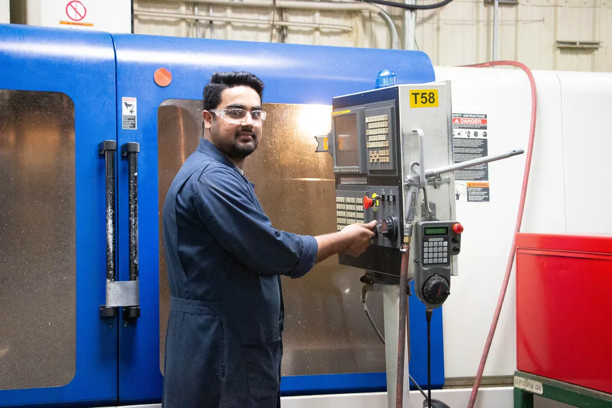 A Clover machinist at a CNC control panel during a production run.