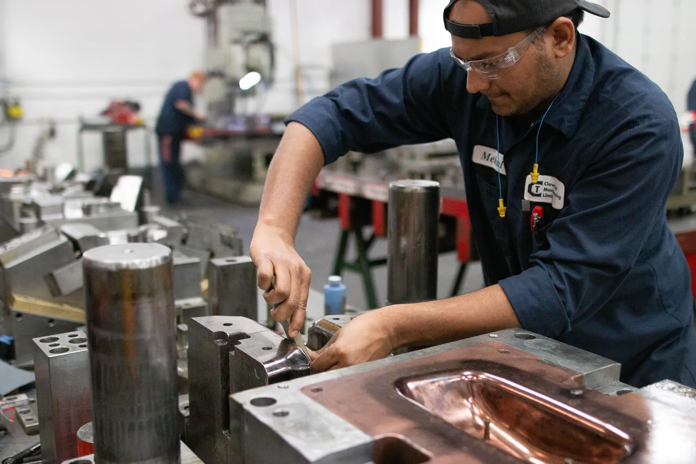 A Clover tool & die maker fitting a progressive die at the bench — hands-on engineering and try-out.