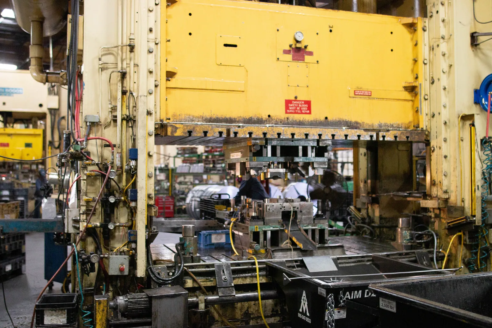 A Clover stamping press running production — tooling loaded and parts feeding through the die.